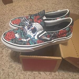 Brand new Vans slip-on shoes featuring a bold skull and roses design.